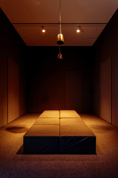 Installation view of a darkened gallery with padded seating