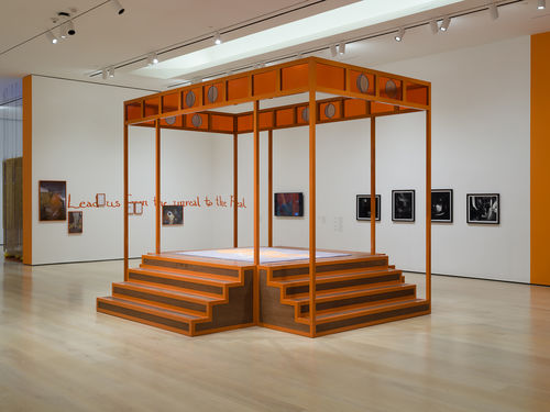 Installation view of an exhibition gallery with orange walls