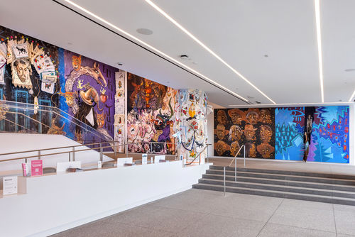 View of a museum lobby, walls covered in colorful murals