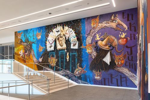 View of a museum lobby, walls covered in colorful murals