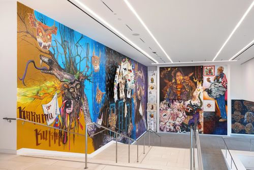 View of a museum lobby, walls covered in colorful murals