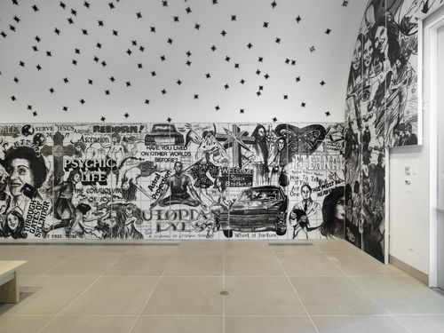 Vault installation featuring a floor-to-ceiling ceramic mural with black-and-white graphics, text, and images of people