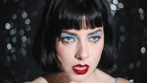Person wearing blue eye shadow and red lipstick against a glittering background