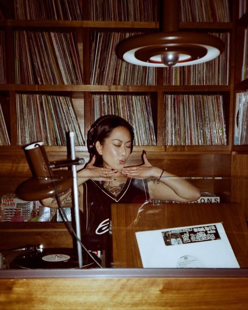 DJ standing in front of a library of vinyl records