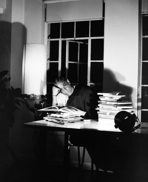 Leilah Weinraub sits at a table behind a stack of books