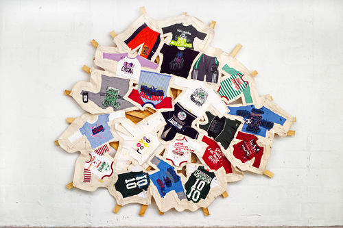 Long-sleeve shirts patched together atop several wooden bars