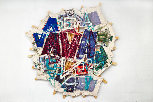 Multicolored shirts patched together atop several wooden bars