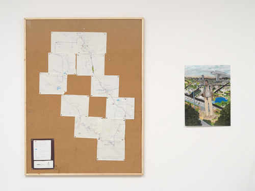 On the left, a cork board with a hand-drawn map pinned in pieces; on the right, a drawing of a giant man standing in a cityscape