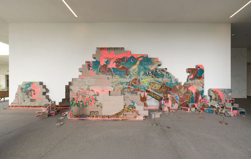 Installation featuring a crumbling wall of cinderblocks with handpainted images and pink neon lights