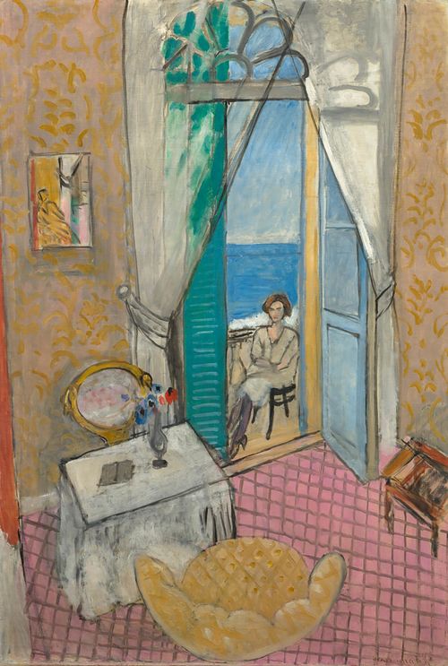 A seated woman seen through an open door, with the ocean visible beyond