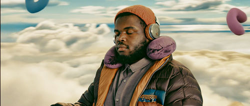 A man in the clouds, wearing a neck pillow around his neck