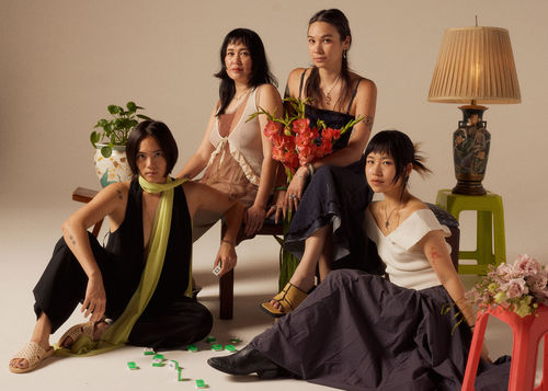 Four women sitting together, mahjong tiles between them
