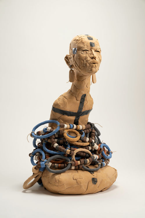 Ceramic figure with long earrings, body enveloped in beaded necklaces