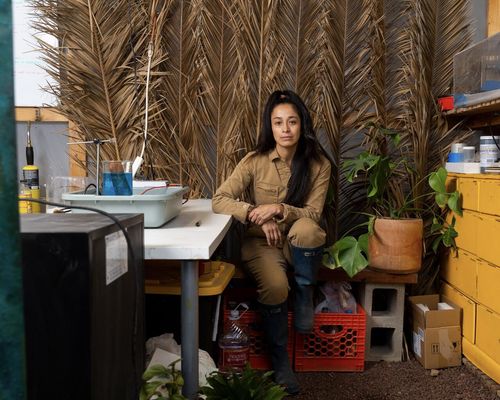 Artist Jackie Amezquita sits in her crowded studio