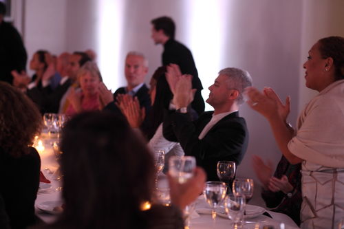 Curator Kellie Jones (standing, right) leads a round of applause at the dinner reception honoring "Now Dig This!" MoMA PS1, Long Island City, NY