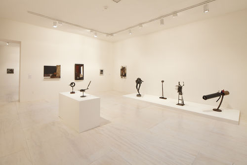 Foreground: six works by John T. Riddle Jr.; background: works by Dale Brockman Davis and Noah Purifoy, "Zulu #4," n.d. Installation view at MoMA PS1, Long Island City, NY