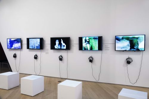 Social Places gallery. On monitors, from left to right: Patssi Valdez, Hot Pink, 1980, Marta Minujín and Rubén Santantonín, La Menesunda (Mayhem), 1965, Ximena Cuevas, Las tres muertes de Lupe (The Three Deaths of Lupe), 1984, Diamela Eltit, Zonas de dolor II (Zones of Pain II), 1982, and Sybil Brintrup and Magali Meneses, La comida (The Meal), 1983. Installation view at Brooklyn Museum, New York
