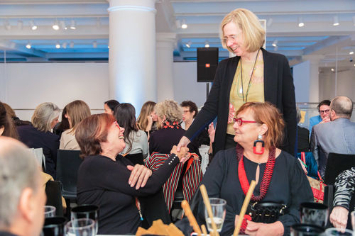 Curator Catherine Morris (standing) shakes hands with artist Graciela Carnevale at the luncheon reception honoring Radical Women. Brooklyn Museum, April 12, 2018
