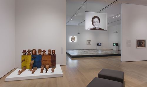Self-Portrait gallery. Foreground: Marisol, Self-Portrait, 1961–62; projected on suspended screen: Lenora de Barros, Homenagem a George Segal (Homage to George Segal), 1984. Installation view at the Hammer Museum, Los Angeles. Installation view at the Hammer Museum, Los Angeles