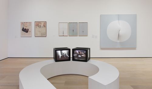 The Erotic gallery. On monitors, from left to right: Silvia Gruner, Nude Descending and The Original Sin/Reproduction, 1986. On wall, from left to right: Karen Lamassonne, two works from the series Baños (Bathrooms), Mercedes Elena González, Vulvosa (tríptico) (Vulviform [triptych]), 1979–81, and Zilia Sánchez, Lunar V (Moon V), 1975. Installation view at the Hammer Museum, Los Angeles