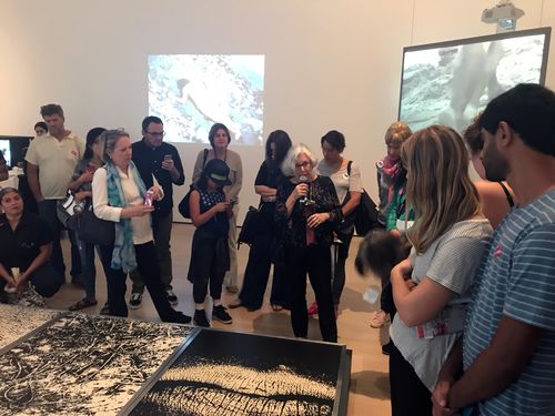 Artist Vera Chaves Barcellos (center, holding microphone) standing over her work Epidermic Scapes, 1977/1982, at the Radical Women artists' walkthrough. Hammer Museum, Los Angeles