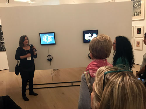 Artist Poli Marichal (left, holding mircrophone) in front of her video Los espejismos de Mandrágora Luna (Mandrágora Luna's phantoms), 1986, at the Radical Women artists' walkthrough. Hammer Museum, Los Angeles