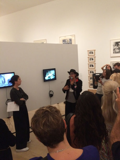 Hammer Museum chief curator Connie Butler (left) and artist Ximena Cuevas (center, holding microphone) in front of Cuevas' video Las tres muertes de Lupe (The Three Deaths of Lupe), 1984, at the Radical Women artists' walkthrough. Hammer Museum, Los Angeles