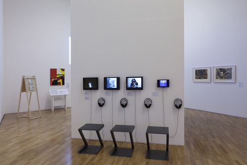 Autorretrato (Self-Portrait) gallery. On monitors, from left to right: Maria Martínez-Cañas, Un problema de identidad (An Identity Problem), 1984, Letícia Parente, Preparação 1 (Preparation 1), 1975, Anna Bella Geiger, Declaração em retrato No. 1 (Statement in Portrait No. 1), 1974, and Margarita Morselli, Autorretrato (Self-portrait), 1984. Installation view at Pinacoteca de São Paulo
