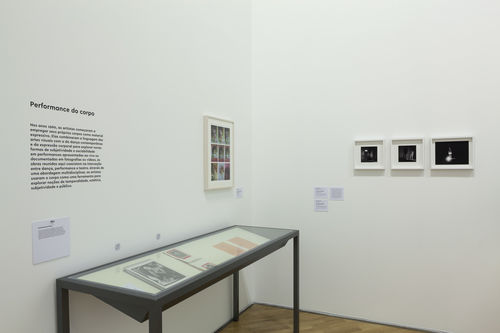 O erótico (The Erotic)/Performance do corpo (Performing the Body) gallery. In vitrine: works by Márcia X.; on wall, from left to right: Delfina Bernal, Declaración de amor a Jeff Perrone (Love letter to Jeff Perrone), 1979, and Margarita Azurdia, Favor quitarse los zapatos (Please take off your shoes), 1970. Installation view at Pinacoteca de São Paulo
