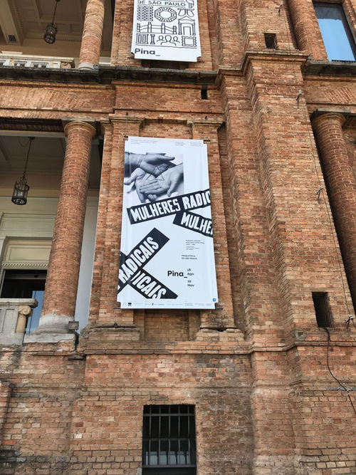 Mulheres Radicais/Mujeres Radicales banner on the museum façade featuring Liliana Porter, Untitled (hands and triangle), 1973. Pinacoteca de São Paulo