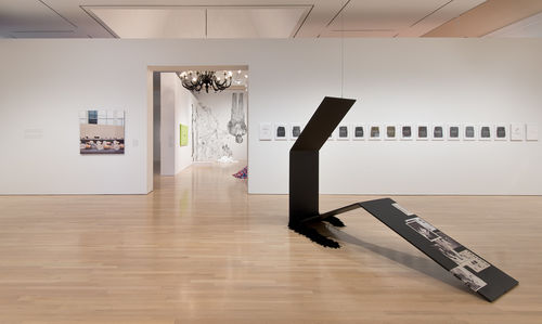 Foreground: Tom Burr, "Propped Perfume," 2008; in same gallery, left wall: Louise Lawler, "Bulbs," 2005–6; right wall: Mary Kelly, "Post-Partum Document: Documentation VI, Pre-writing Alphabet, Exergue and Diary," 1978; in next gallery: works by Jenny Holzer, Felix Gonzalez-Torres, Rirkrit Tiravanija, and Fred Wilson. Installation view at the Hammer Museum, Los Angeles