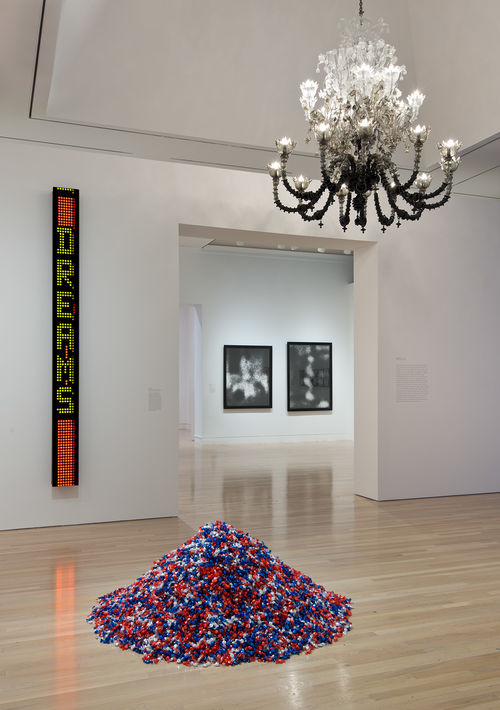 On floor: Felix Gonzalez-Torres, "'Untitled' (USA Today)," 1990; from ceiling, Fred Wilson, "To Die Upon a Kiss," 2011; on wall: Jenny Holzer, "Laments: I am a man . . . ," 1987; next gallery: two works by Allan McCollum. Installation view at the Hammer Museum, Los Angeles