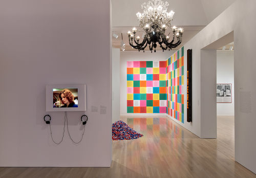 Foreground: Judith Barry, "Casual Shopper," 1980–81; next gallery, on floor: Felix Gonzalez-Torres, "'Untitled' (USA Today)," 1990; from ceiling, Fred Wilson, "To Die Upon a Kiss," 2011; on wall, from left to right: Jenny Holzer, "Inflammatory Essays," 1979–81, and "Laments: I am a man . . . ," 1987. Installation view at the Hammer Museum, Los Angeles 