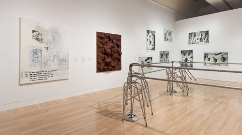 Foreground: Cady Noland, "Frame Device," 1989; on wall, from left to right: Sue Williams, "Spiritual America," 1992, John Miller, "Untitled," 1990, and Zoe Leonard, "Trophies," 1990. Installation view at the Hammer Museum, Los Angeles