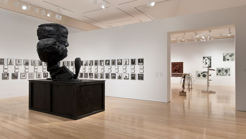 Foreground: Paul McCarthy, "Michael Jackson Fucked Up Big Head Big Foot (MJFUBH)," 2010. On wall:  Glenn Ligon, "Notes on the Margin of the 'Black Book,'" 1991–93. In next gallery: works by Jimmie Durham, Cady Noland, John Miller, and Zoe Leonard. Installation view at the Hammer Museum, Los Angeles