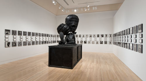 On floor: Paul McCarthy, "Michael Jackson Fucked Up Big Head Big Foot (MJFUBH)," 2010. On wall:  Glenn Ligon, "Notes on the Margin of the 'Black Book,'" 1991–93. Installation view at the Hammer Museum, Los Angeles
