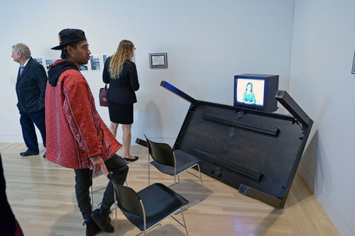 A guest studies Adrian Piper, "Cornered," 1988, during the opening of "Take It or Leave It," Hammer Museum, Los Angeles, February 8, 2014