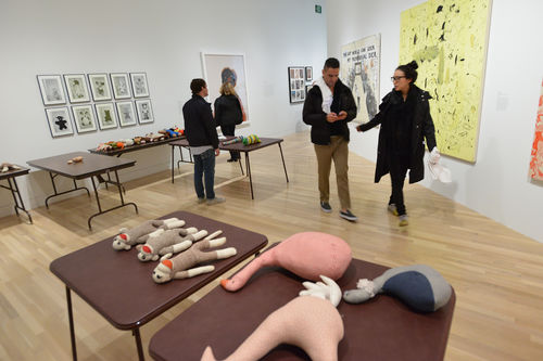Guests in gallery with Mike Kelley, "Craft Morphology Flow Chart," 1991, works by Fred Wilson, Paul McCarthy, and Sue Williams during the opening of "Take It or Leave It," Hammer Museum, Los Angeles, February 8, 2014