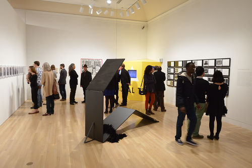 Guests in gallery with Tom Burr, "Propped Perfume," 2008, works by Mary Kelly, Adrian Piper, and Martha Rosler during the opening of "Take It or Leave It," Hammer Museum, Los Angeles, February 8, 2014