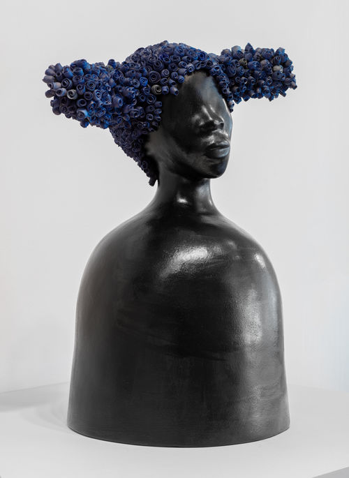 A black clay bust with bright blue pigtails on either side of her head
