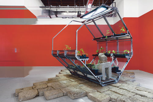 Beatriz Cortez and Rafa Esparza, Nomad 13, 2017. Adobe bricks, steel, concrete, hammer, plastic, paper, soil, plants: corn, black bean, prickly pear, sorghum, amaranth, quinoa, chayote squash, chia, chili pepper, yerba buena, yerba santa, sage, ceiba tree. 104 x 84 x 96 in. (264.2 x 213.4 x 243.8 cm). Installation view, Mundos Alternos, UCR ARTSblock, Riverside, CA, September 16, 2017–February 4, 2018. Courtesy UCR ARTSblock. Photo: Nikolay Maslov.