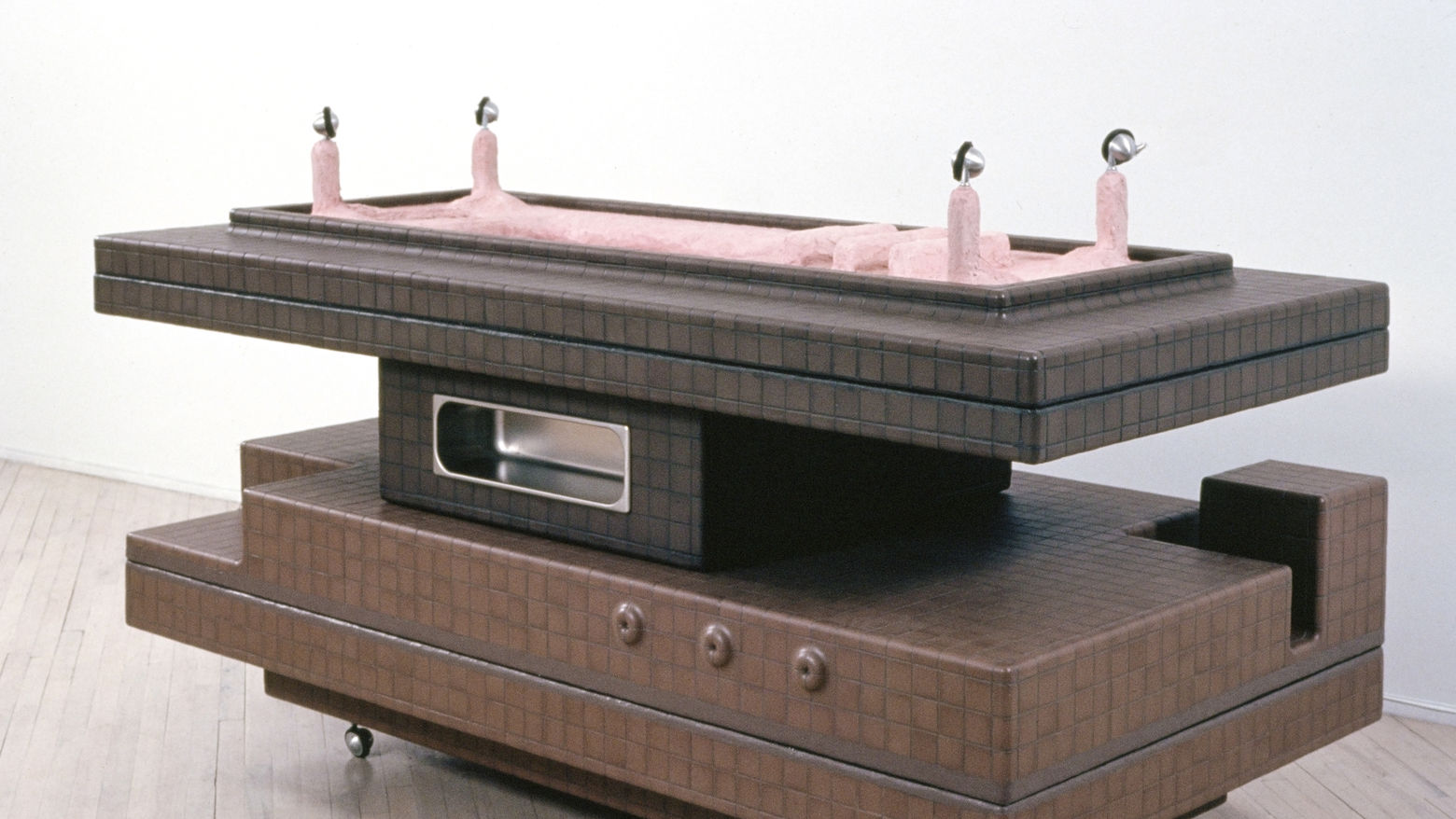 A brown table-like sculpture with pink legs on top