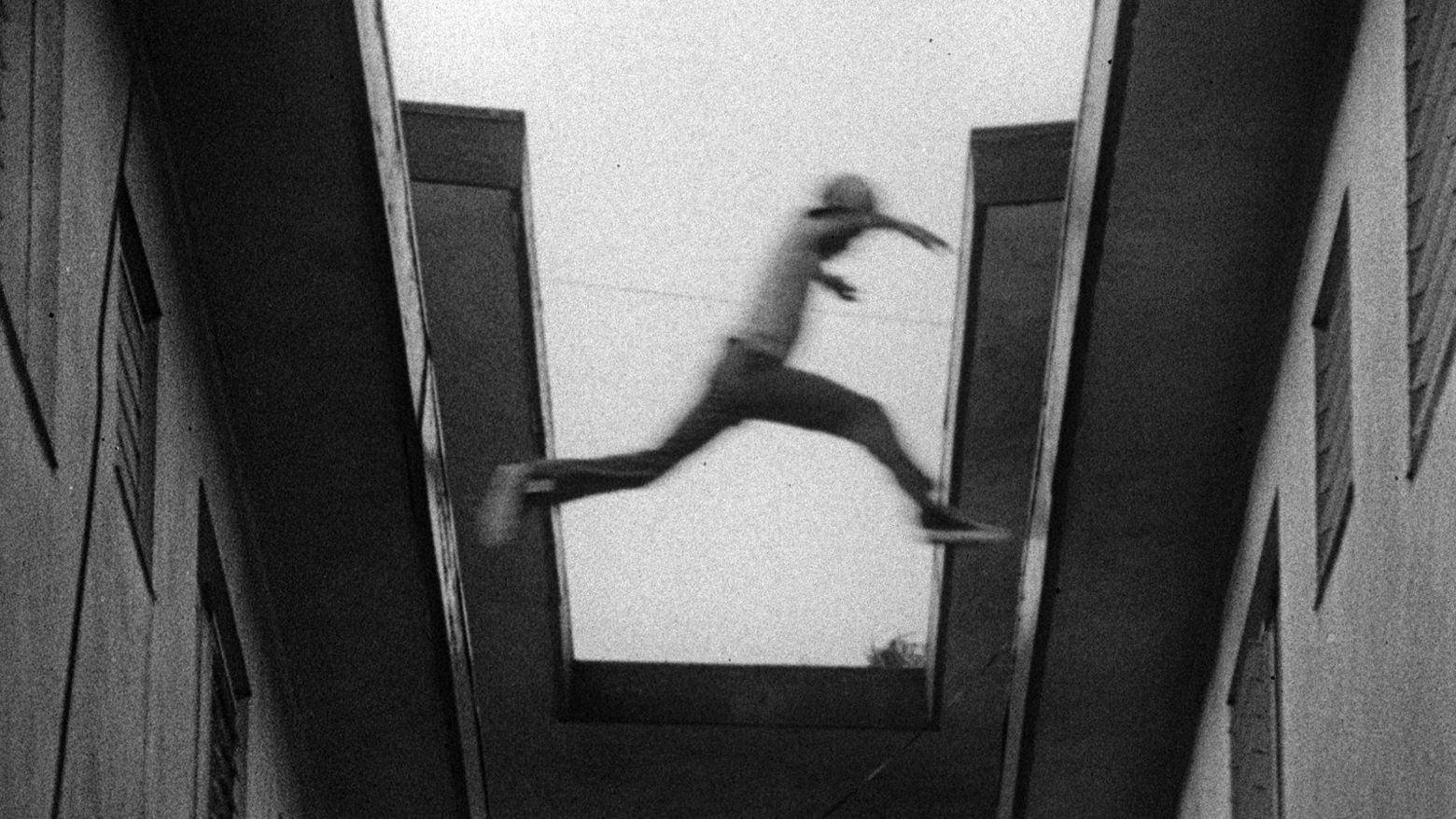Still from the film Killer of Sheep (1978) showing a boy leaping from one rooftop to another