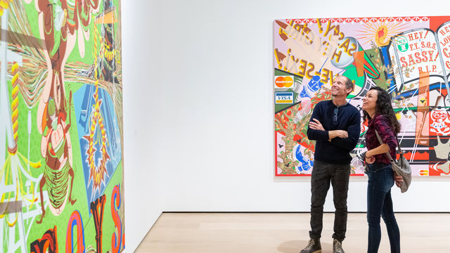 Two people look up at a large painting in a gallery