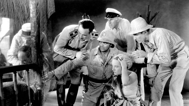 Still from the film Safe in Hell (1931) showing a woman on the ground with a group of soldiers