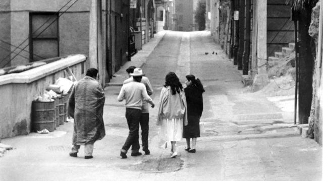 Still from the film The Exiles (1961) showing a group of people walking down an alley