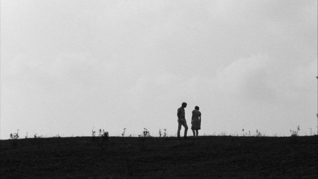 Still from the film Spring Night, Summer Night (1967) showing two people standing on a hill, in shadow