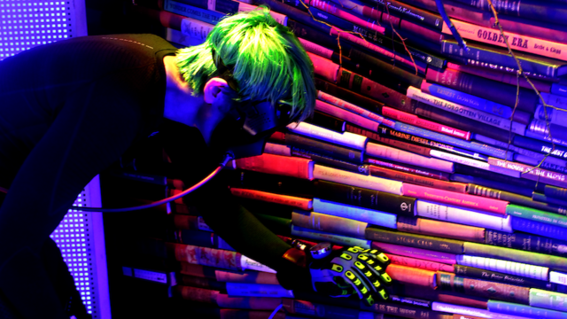 A man in a mask and gloves examines a stack of books