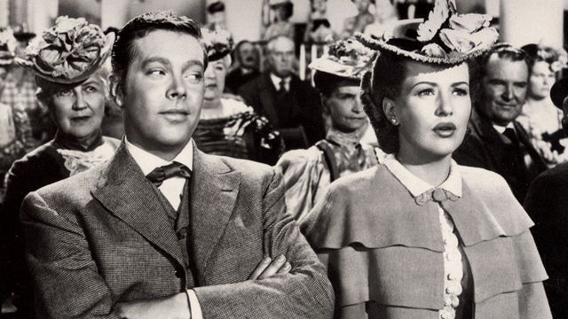 Still from the film The Shocking Miss Pilgrim (1947) showing a man looking askance at a women seated next to him