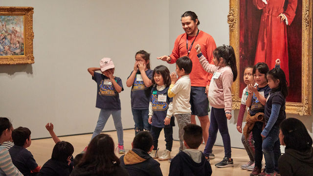 A group of students stand before another group sitting on the ground, posing.